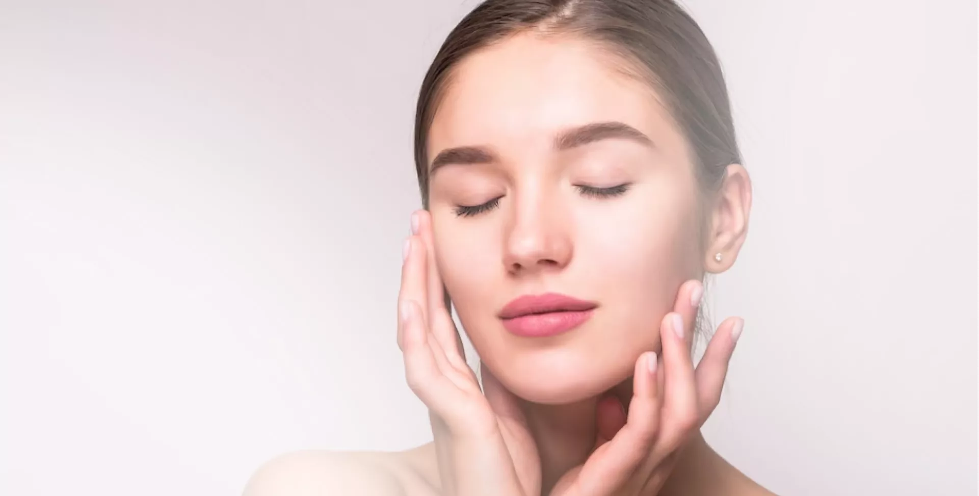 Woman with closed eyes gently touching her face.